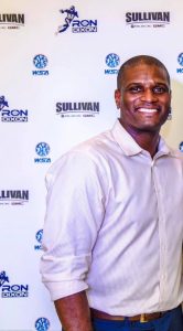 Ron Dixon smiling in front of a Ron Dixon Foundation backdrop.