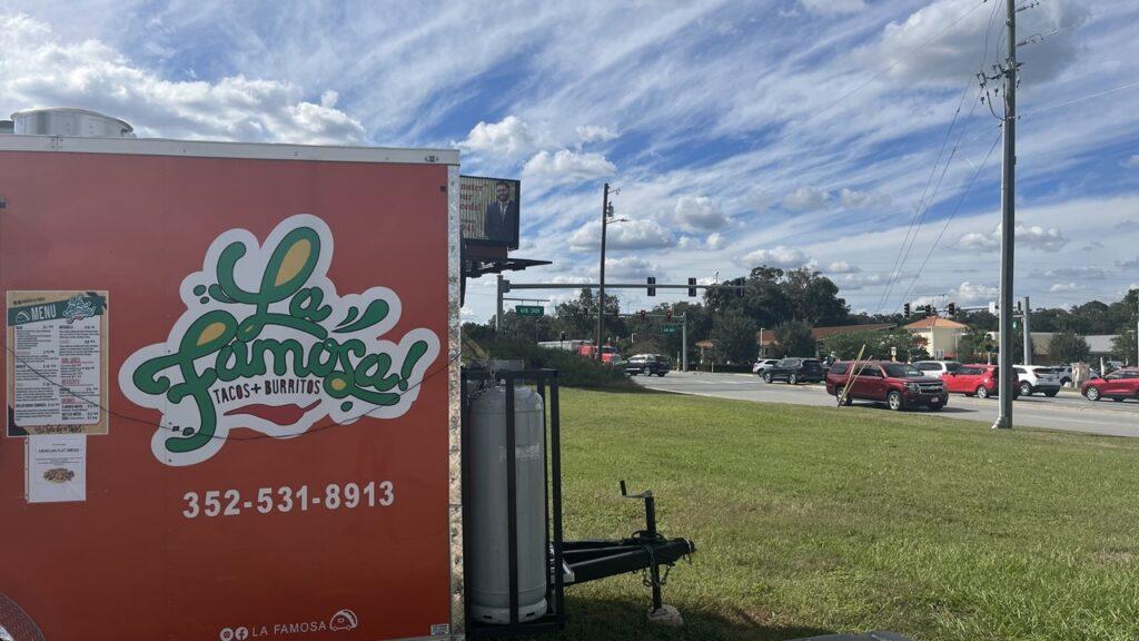 The red Taqueria La Famosa food truck parked beside a grassy lot.