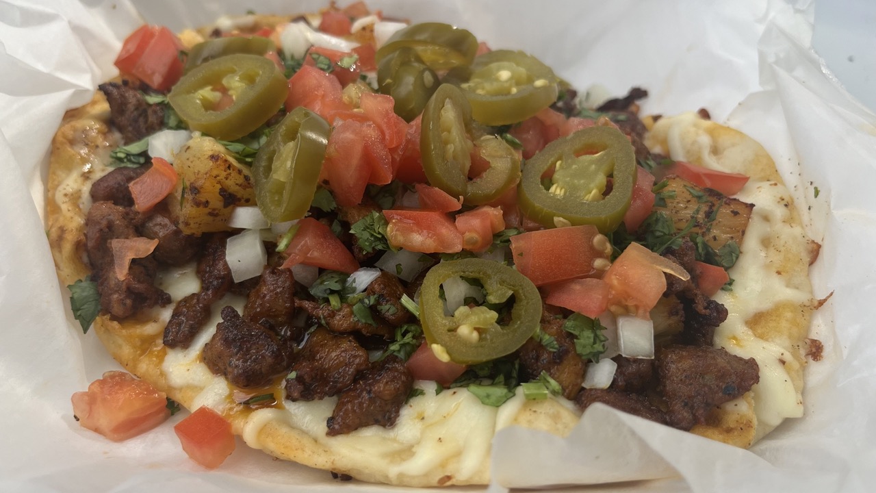 A Taqueria La Famosa flatbread topped with grilled meat, melted cheese, diced tomatoes, onions, cilantro and pickled jalapeños.